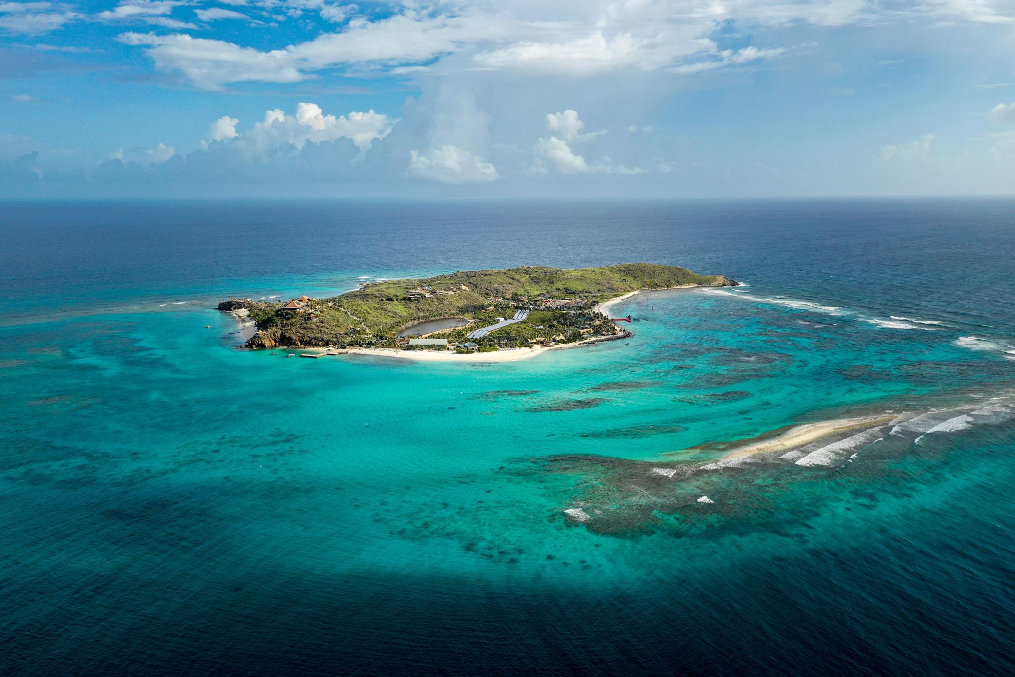 An island ringed by turquoise water and reef, seen from the air