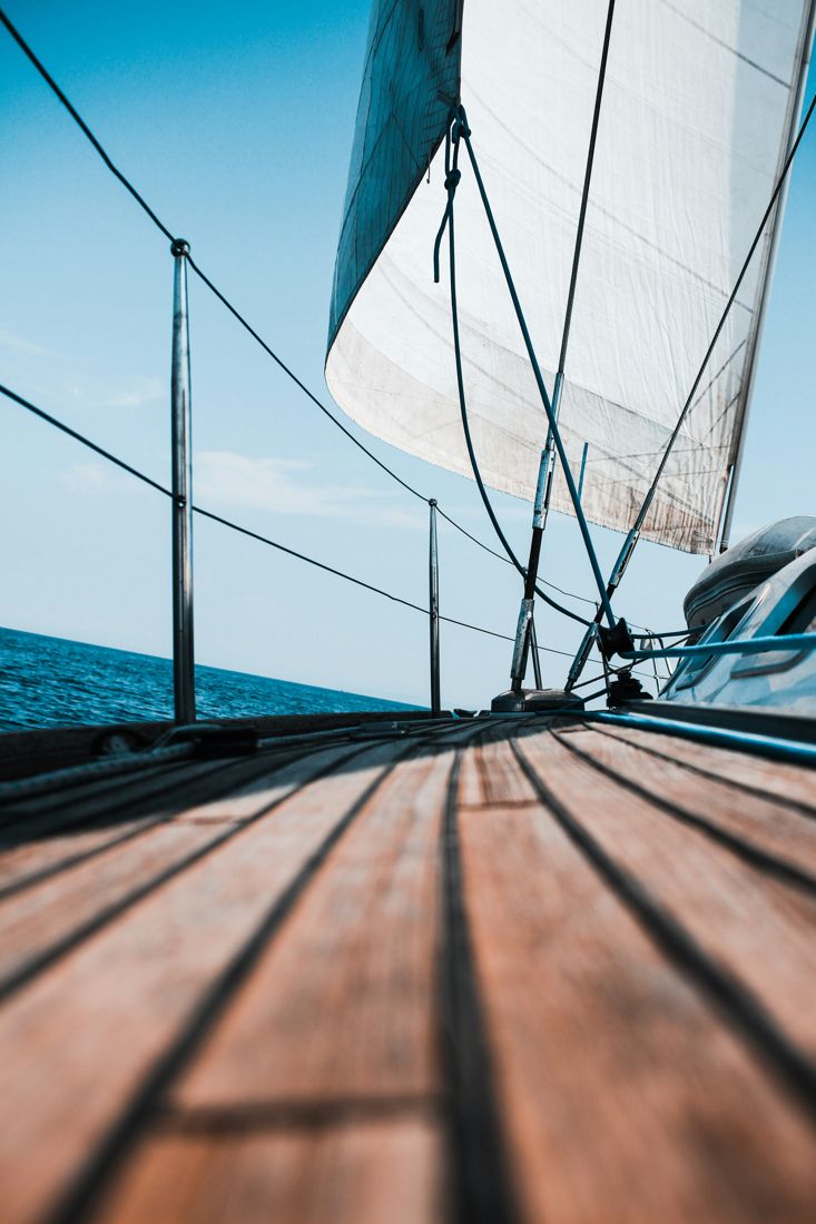 Looking down the teak deck of a sailboat under sail on a clear day