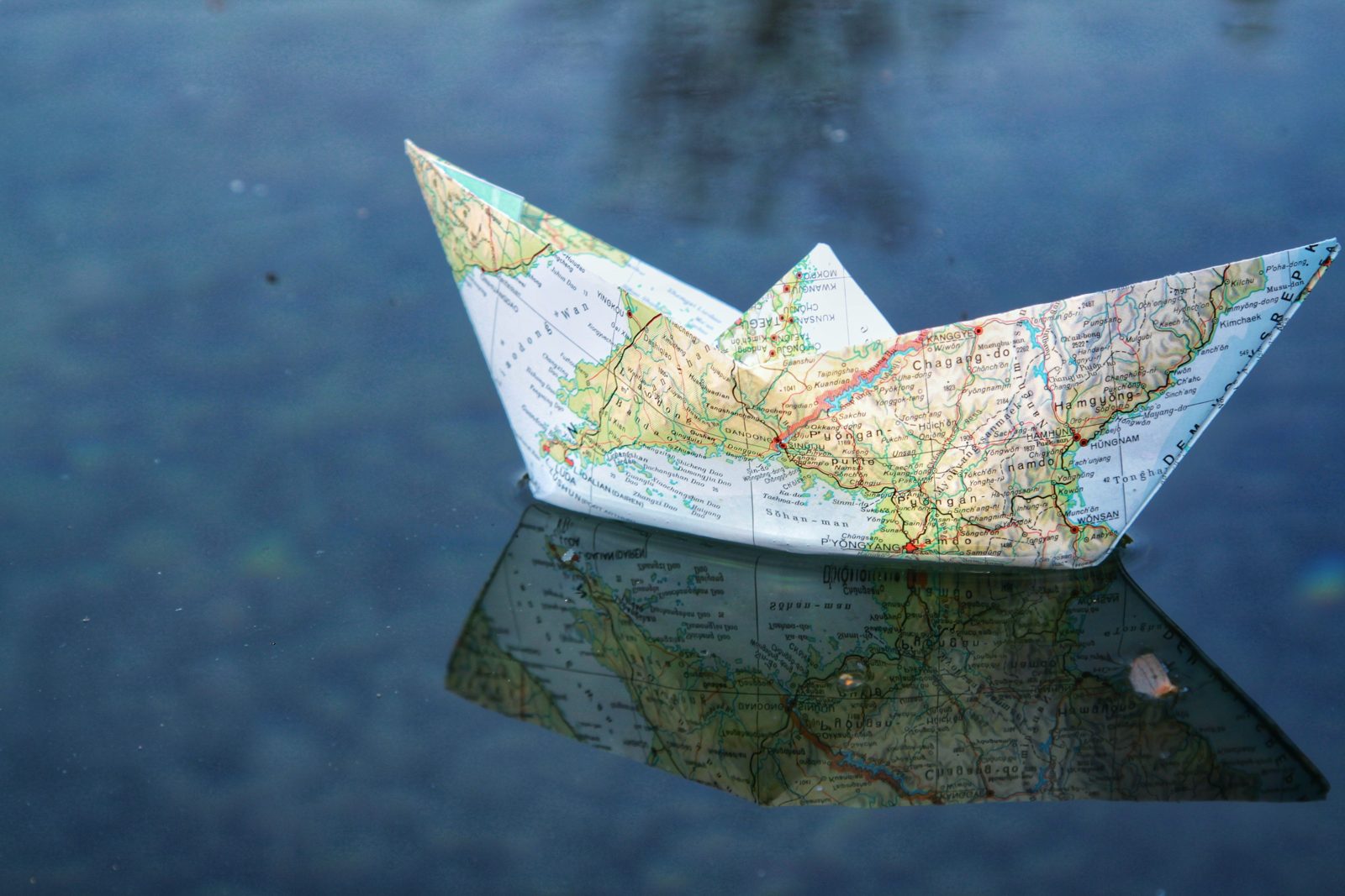 Paper boat folded from a map, floating on water